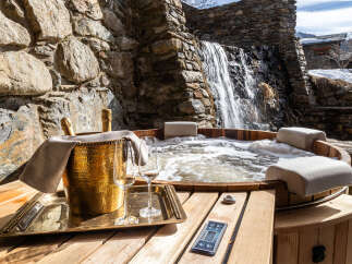 Indulge in luxury and relaxation at this stunning property featuring a private hot tub with a cascading waterfall backdrop.