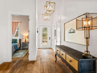 Step into this inviting entryway, showcasing beautiful hardwood floors and stylish lighting fixtures.