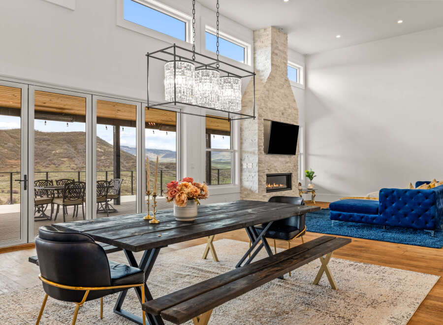 Experience luxury living in this stunning property featuring a modern dining area with a rustic wooden table and elegant chandelier.