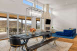 Experience luxury living in this stunning property featuring a modern dining area with a rustic wooden table and elegant chandelier.