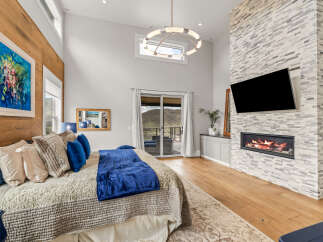 This luxurious bedroom boasts a stunning fireplace and a large flat-screen TV, perfect for cozy nights in.