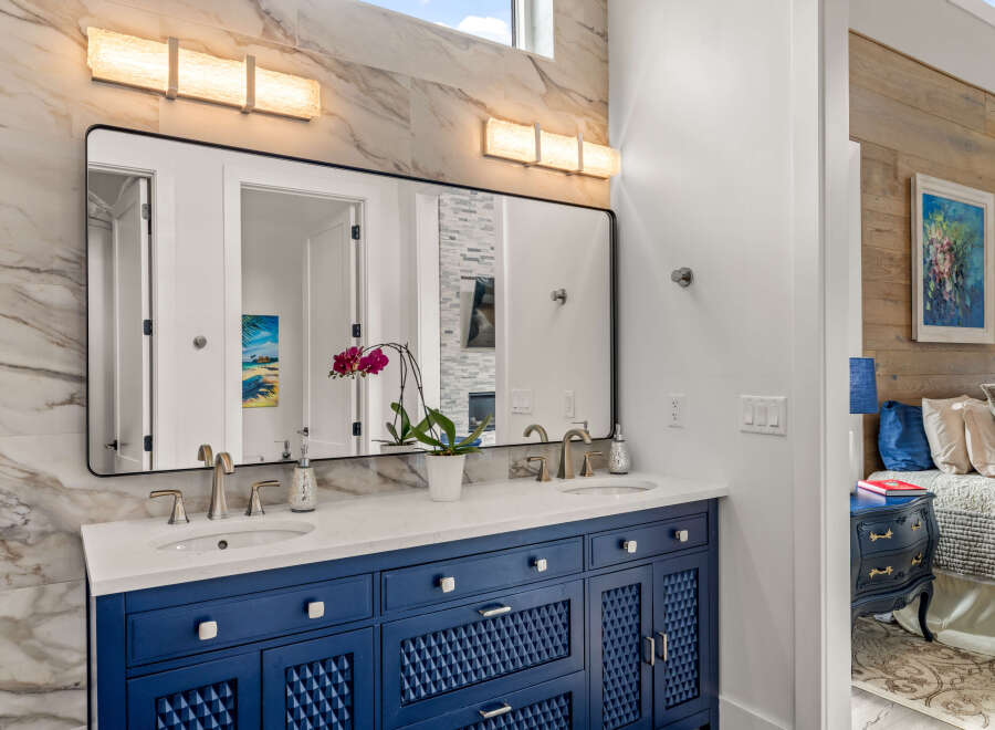 This stunning bathroom features a modern vanity with a striking blue finish, complemented by a sleek countertop and stylish faucets.