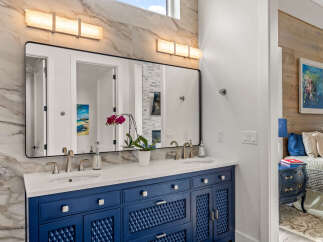 This stunning bathroom features a modern vanity with a striking blue finish, complemented by a sleek countertop and stylish faucets.