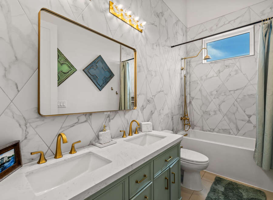 Step into luxury with this stunning bathroom! Featuring a sleek marble design, gold fixtures, and a spacious vanity, this space is perfect for relaxation.