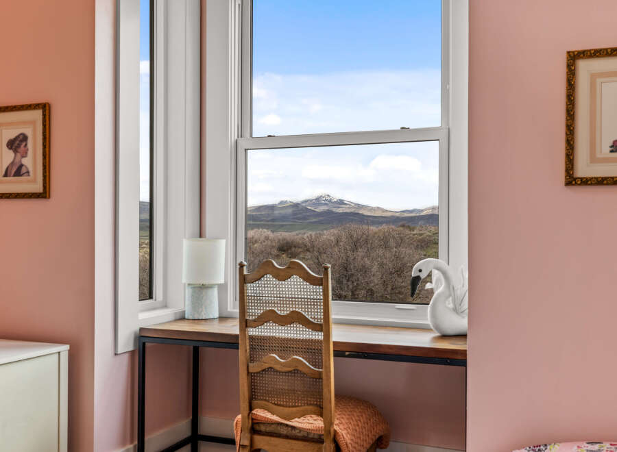 This charming property features a cozy desk area with a stunning view of the mountains through a large window.