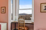 This charming property features a cozy desk area with a stunning view of the mountains through a large window.