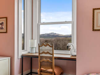 This charming property features a cozy desk area with a stunning view of the mountains through a large window.