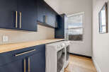 This stunning laundry room boasts modern design with navy blue cabinetry and sleek gold hardware.