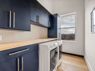 This stunning laundry room boasts modern design with navy blue cabinetry and sleek gold hardware.