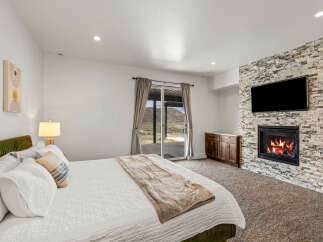 This luxurious bedroom boasts a cozy fireplace and a large flat-screen TV, perfect for relaxing evenings.