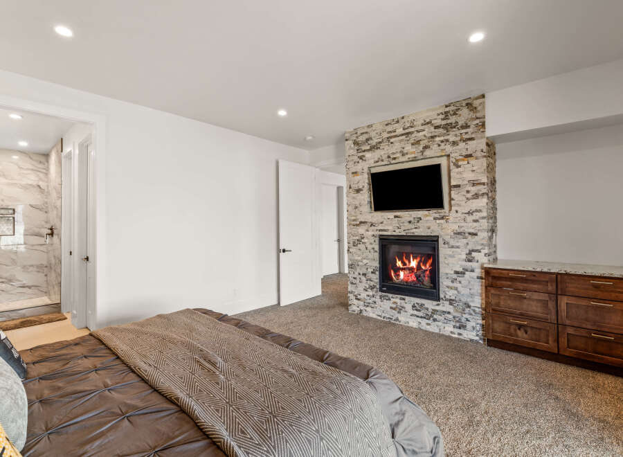 This luxurious bedroom boasts a cozy fireplace with a mounted TV, perfect for relaxing evenings.