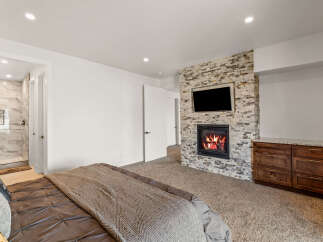 This luxurious bedroom boasts a cozy fireplace with a mounted TV, perfect for relaxing evenings.