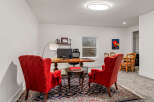 Step into this elegant home office, featuring a spacious wooden desk and two plush red armchairs, perfect for focused work or client meetings.