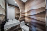 This stunning powder room showcases a unique artistic flair with its custom mountain mural wallpaper.