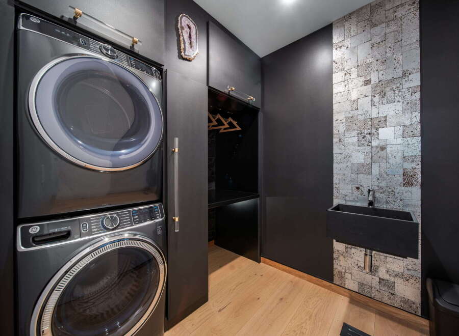 This modern laundry room boasts a sleek design with a stacked washer and dryer, offering both style and functionality.