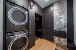 This modern laundry room boasts a sleek design with a stacked washer and dryer, offering both style and functionality.