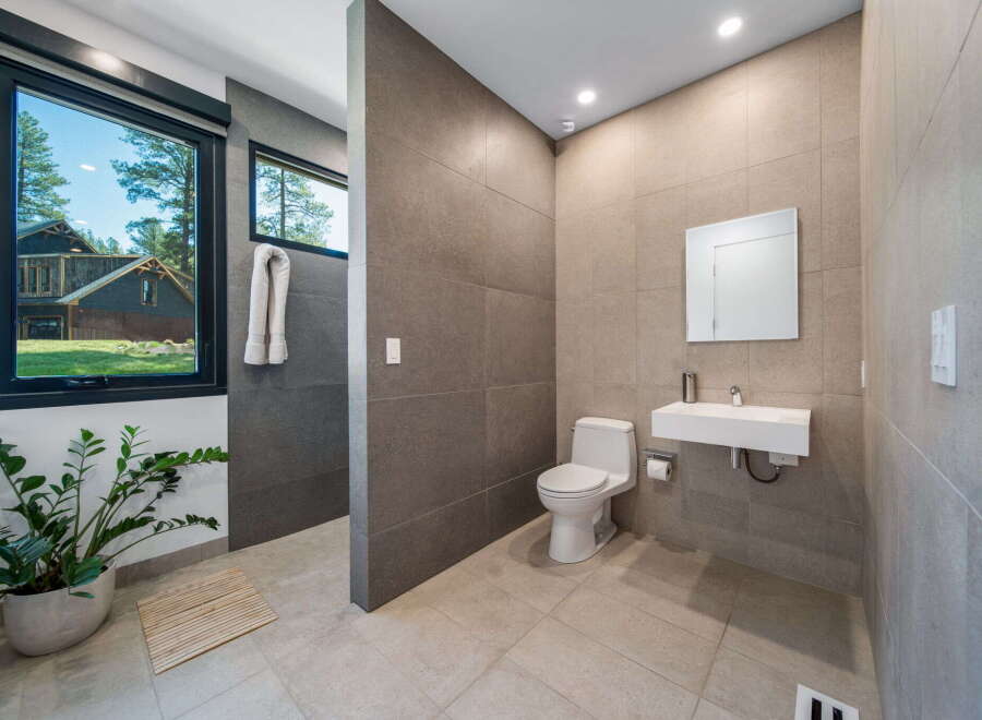 Step into a modern bathroom oasis! This stunning space features sleek tile work, a contemporary sink, and a pristine toilet.