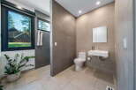 Step into a modern bathroom oasis! This stunning space features sleek tile work, a contemporary sink, and a pristine toilet.