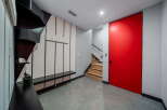 This modern entryway showcases a striking red door and a unique black staircase.