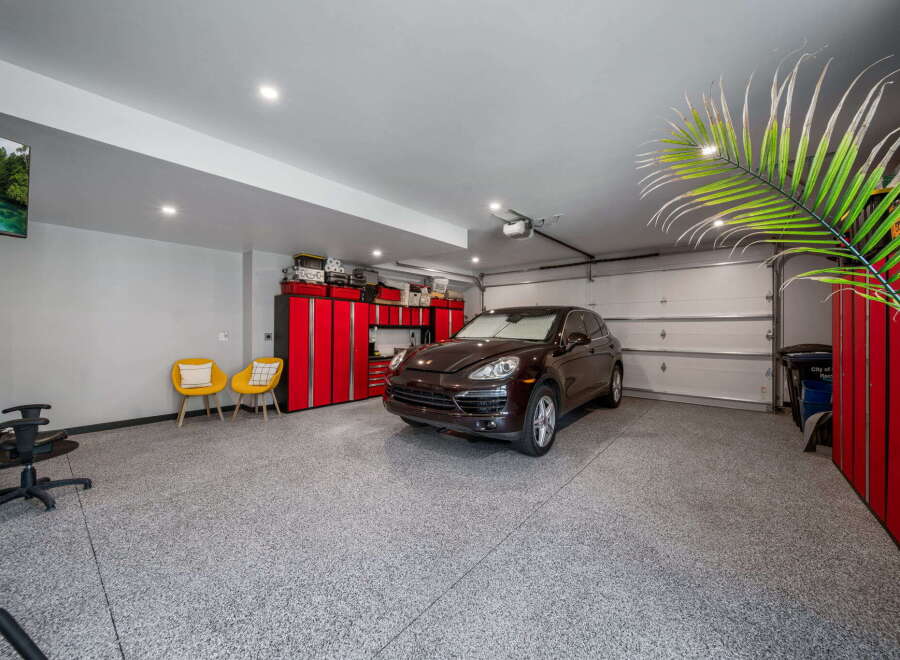 Step into luxury with this stunning garage, featuring a sleek epoxy floor and ample space for your vehicles and hobbies.
