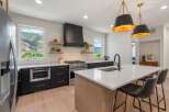 This stunning kitchen boasts modern design with sleek black cabinetry and a contrasting white countertop.