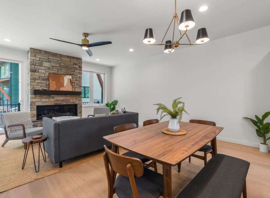 Step into modern elegance with this stunning property, featuring a cozy living room with a stone fireplace and a stylish dining area.
