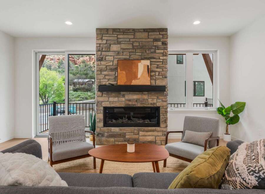Experience the epitome of modern living in this stunning property, featuring a cozy living room with a stone fireplace.