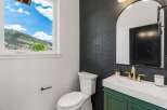 This stunning bathroom features a modern design with a sleek black tiled wall and a stylish green vanity.