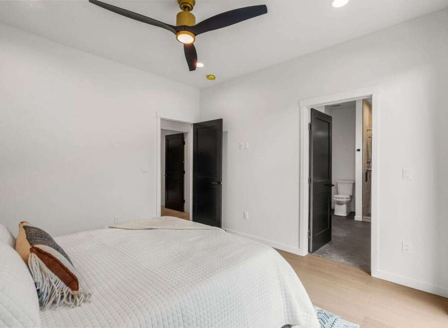 Step into this modern bedroom featuring a stylish ceiling fan and sleek black doors.
