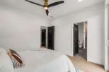 Step into this modern bedroom featuring a stylish ceiling fan and sleek black doors.