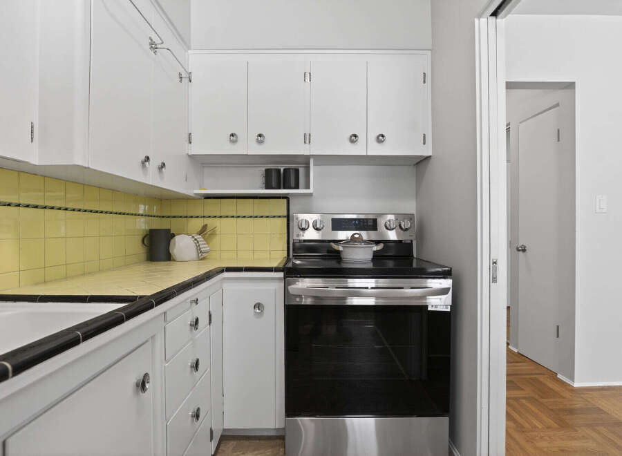 Step into this charming kitchen, featuring classic white cabinetry and a sleek black countertop.