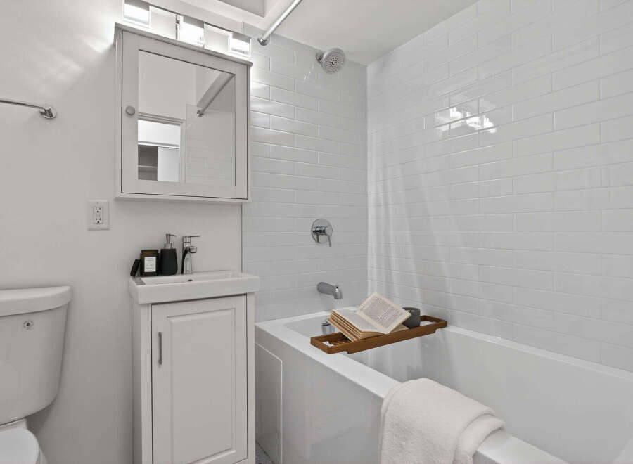 This modern bathroom features a sleek, minimalist design with bright white subway tiles and a clean, contemporary vanity.