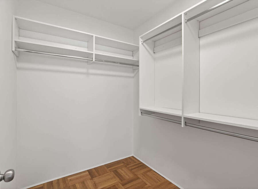 Step into this spacious walk-in closet, offering ample storage with its built-in shelves and hanging rods.