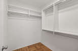 Step into this spacious walk-in closet, offering ample storage with its built-in shelves and hanging rods.