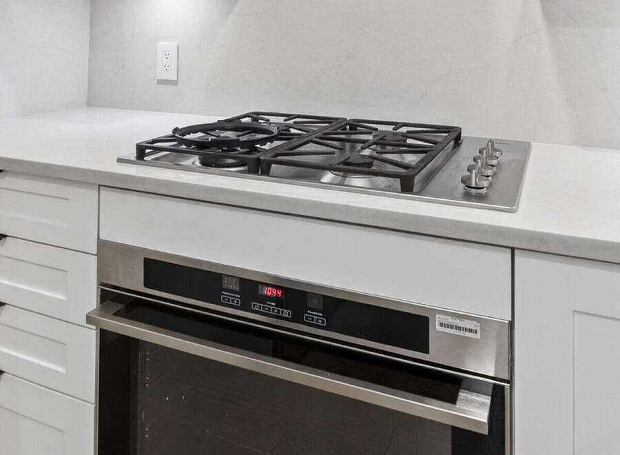 This modern kitchen boasts sleek, white cabinetry and a stainless steel oven, perfect for culinary enthusiasts.