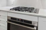This modern kitchen boasts sleek, white cabinetry and a stainless steel oven, perfect for culinary enthusiasts.
