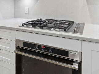 This modern kitchen boasts sleek, white cabinetry and a stainless steel oven, perfect for culinary enthusiasts.