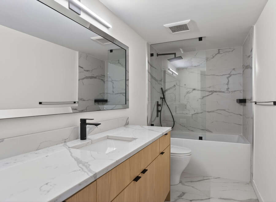 This modern bathroom features a sleek design with a marble countertop and a wooden vanity.