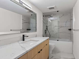 This modern bathroom features a sleek design with a marble countertop and a wooden vanity.