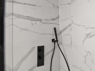 Step into luxury with this stunning bathroom featuring a sleek black showerhead and fixtures.