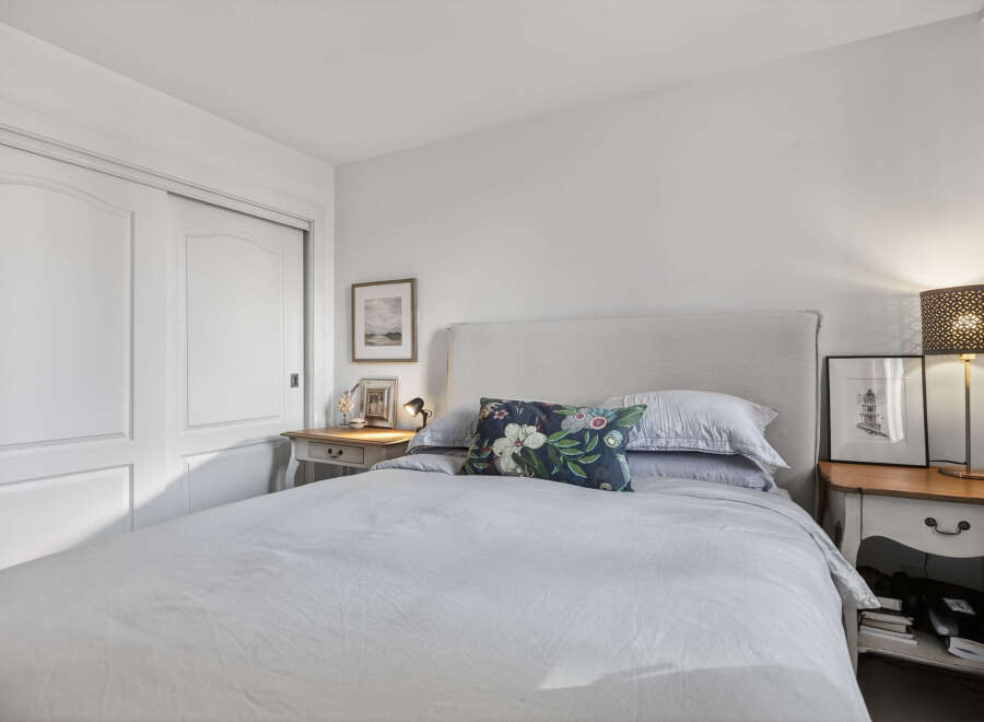 This cozy bedroom offers a serene retreat with its neutral color palette and ample natural light.