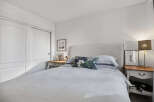 This cozy bedroom offers a serene retreat with its neutral color palette and ample natural light.