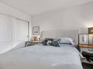 This cozy bedroom offers a serene retreat with its neutral color palette and ample natural light.