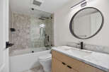 Step into a modern bathroom oasis! This stunning space features a sleek, round mirror and a stylish vanity with a marble countertop.