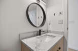 This modern bathroom features a sleek, round mirror and a stylish black faucet.