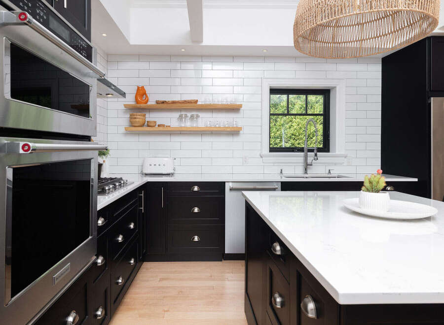 This stunning kitchen boasts modern design with sleek black cabinetry and pristine white countertops, creating a sophisticated and inviting atmosphere.