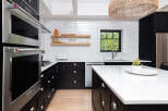 This stunning kitchen boasts modern design with sleek black cabinetry and pristine white countertops, creating a sophisticated and inviting atmosphere.