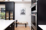 This modern kitchen boasts sleek black cabinetry, offering ample storage and a sophisticated aesthetic.