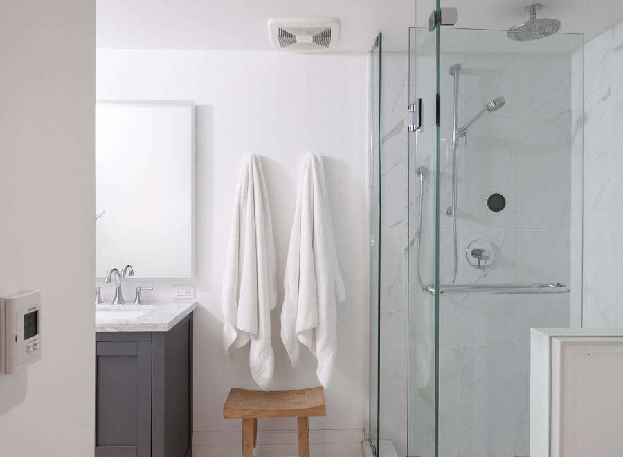 Step into a beautifully designed bathroom featuring a modern glass shower enclosure and elegant marble-look tiles.