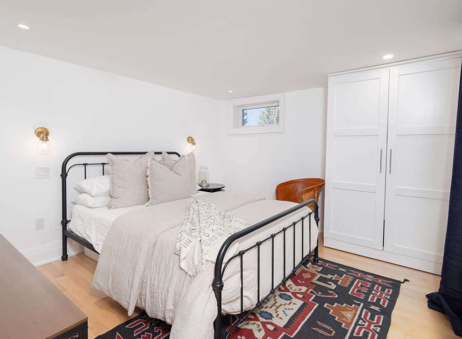 This cozy bedroom features a stylish black metal bed frame, complemented by a neutral color palette and hardwood floors.